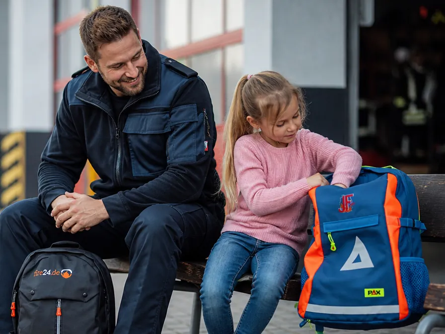 Feuerwehrmann und Kind mit PAX- und fire24-Rucksack